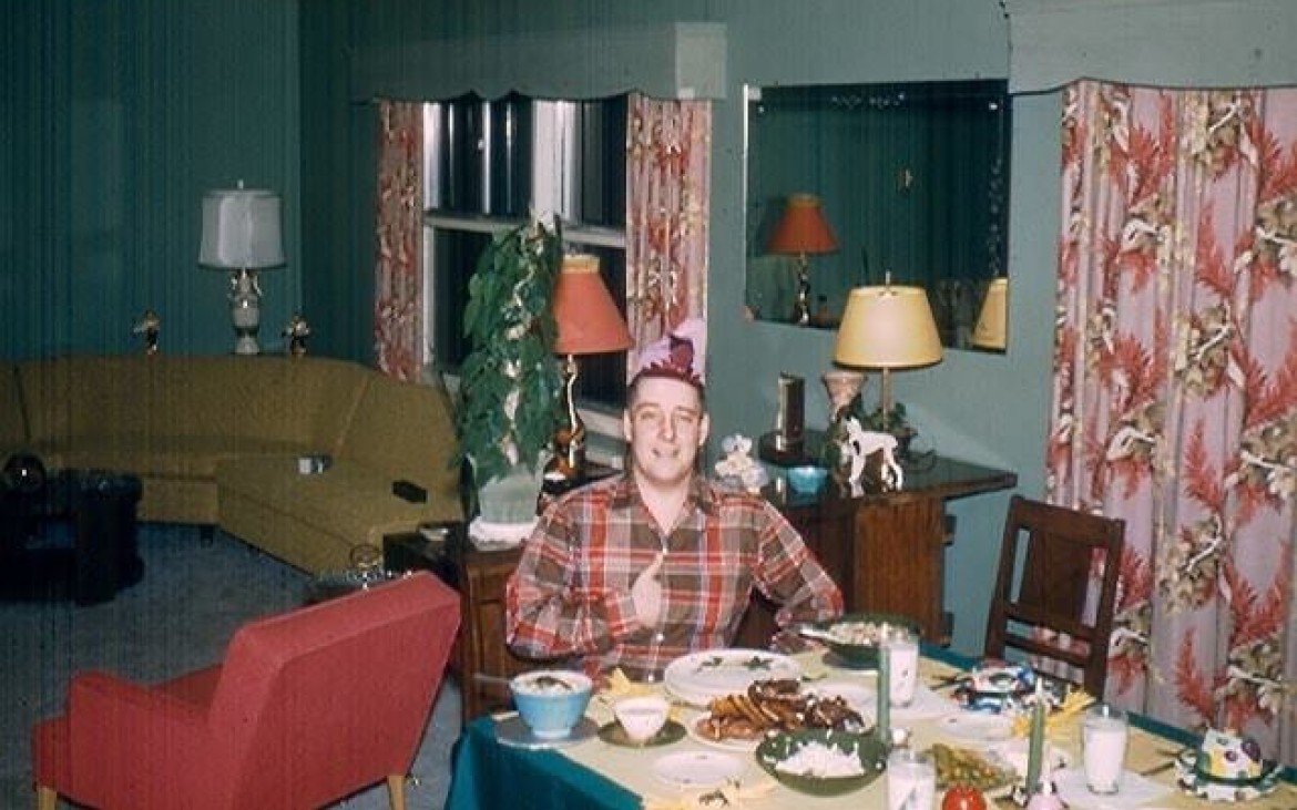 Ron Vaulkenburg sent us this photo of his grandfather taken on his 40th birthday in 1954.  Everything in this photo screams 1950's Americana, from the curtains to the corner sofa, to what looks like Pyrex on the table, one thing above all stands out that's grandad's Napoleon pose with his hand in his shirt and undersized Napolean hat. It typifies the 'dad joke'.  You can't help but smile.